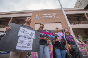 Cuatro mujeres trans con pancartas y signos en protesta frente al Ministerio Público de Honduras. Marcha del Día Internacional de la Eliminación de la Violencia contra la Mujer, Tegucigalpa, 2019.